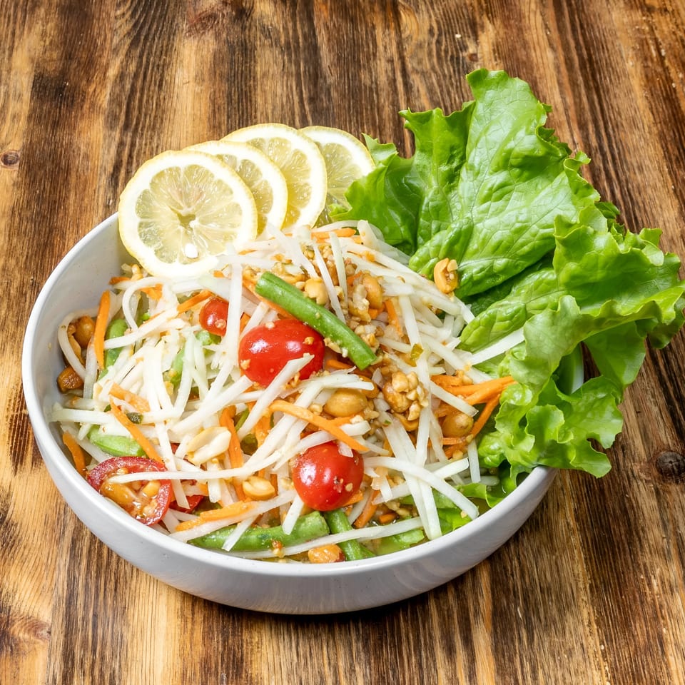 A vibrant Thai papaya salad with shredded papaya, carrots, tomatoes, green beans, and peanuts.