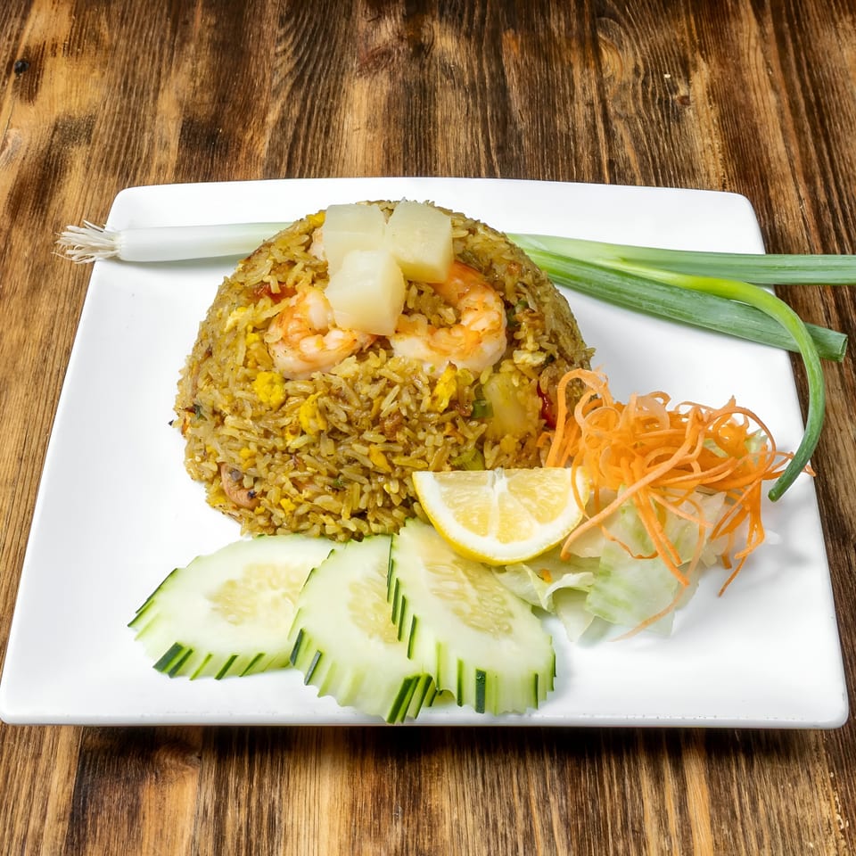 Link Thai pineapple fried rice with shrimp, cucumber, lemon, shredded carrots, and scallions.