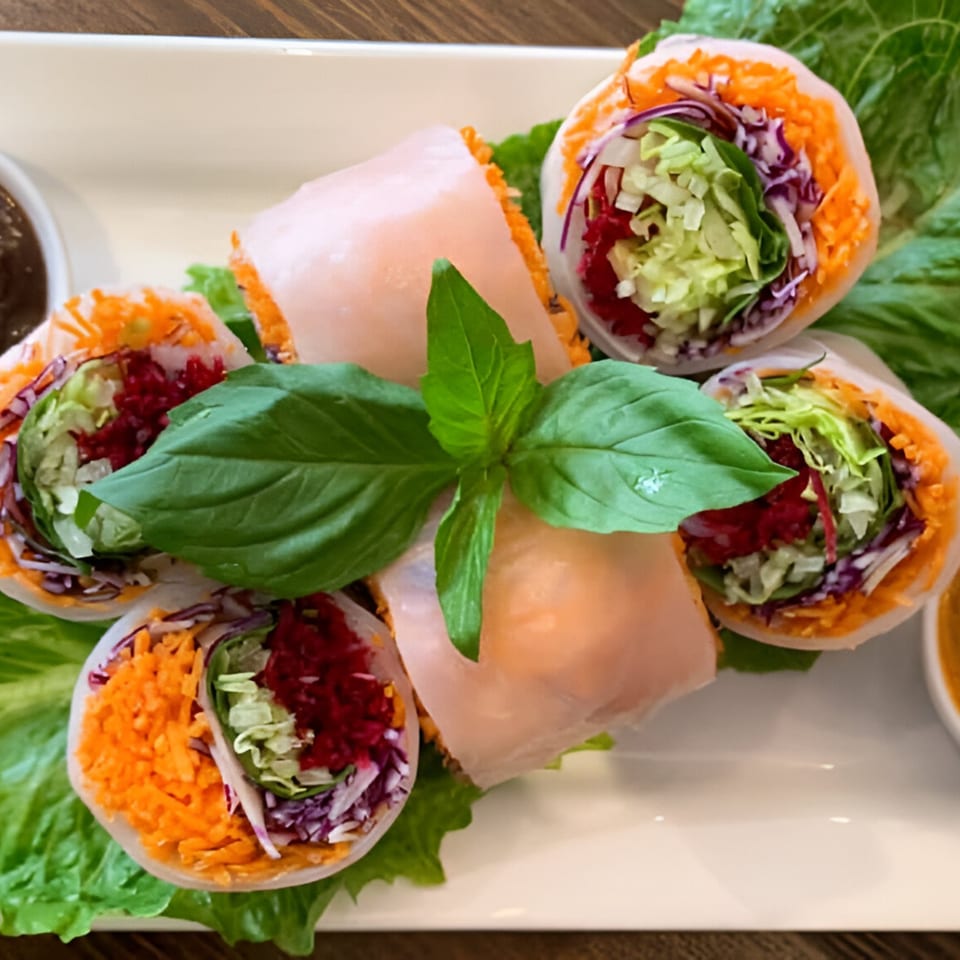 Fresh Thai spring rolls with shredded carrots, cabbage, and lettuce, garnished with basil.